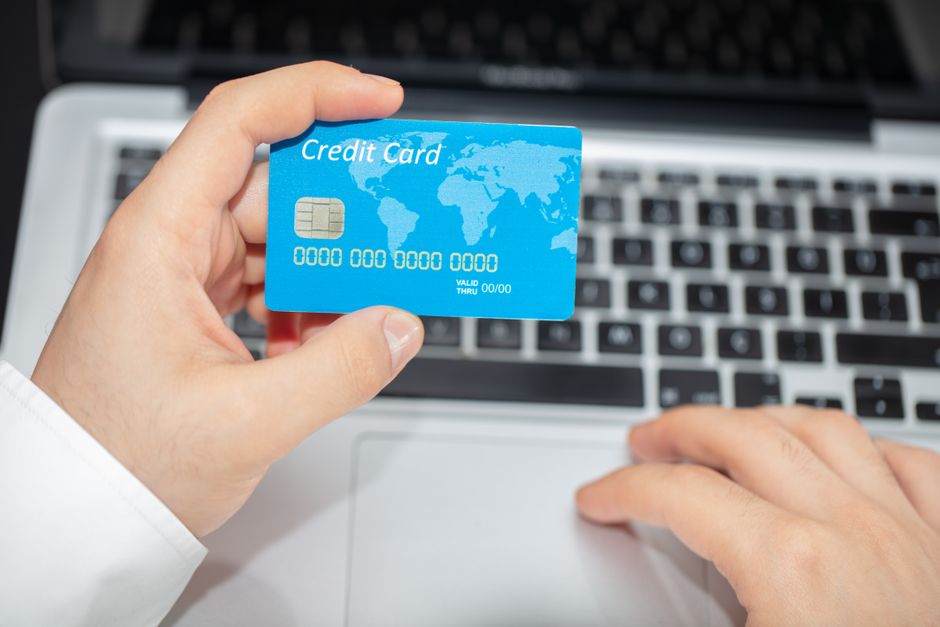 Personne regardant un ordinateur portable avec un site de commerce en ligne, avec une expression choquée et un chariot en arrière-plan.