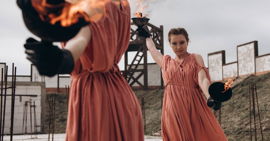 Two women in flowing dresses performing an impressive fire dance with flaming torches.
