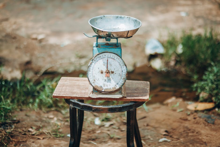 Close-up of an old-fashioned weighing scale placed outdoors on a wooden platform.